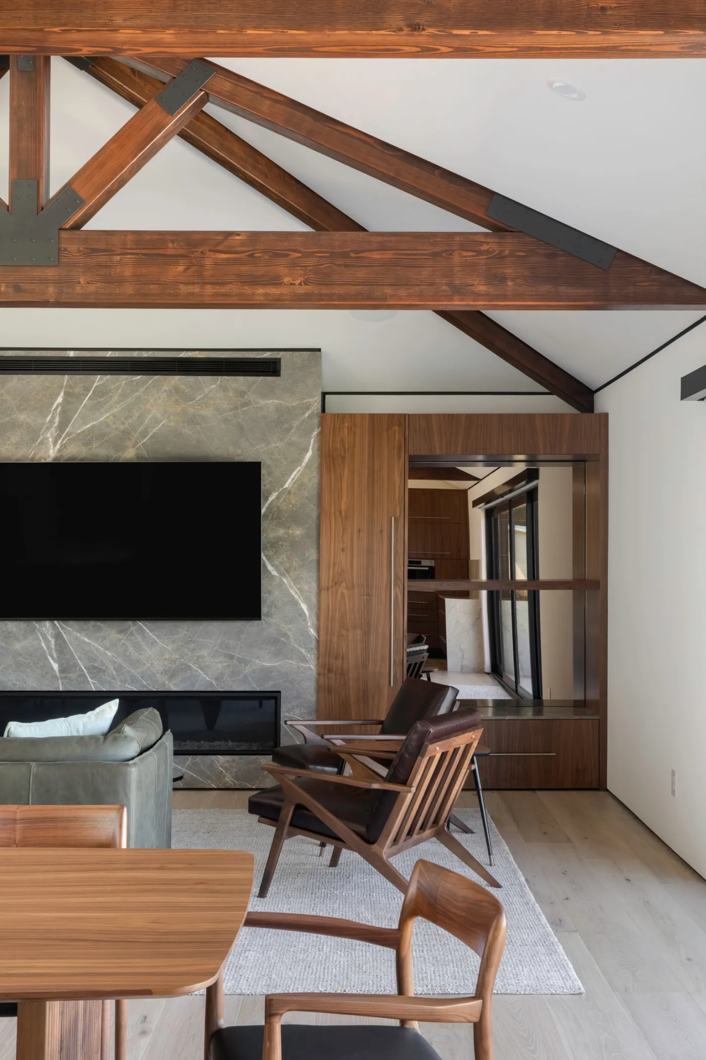 Vaulted living space with exposed timber trusses and a stone fireplace wall