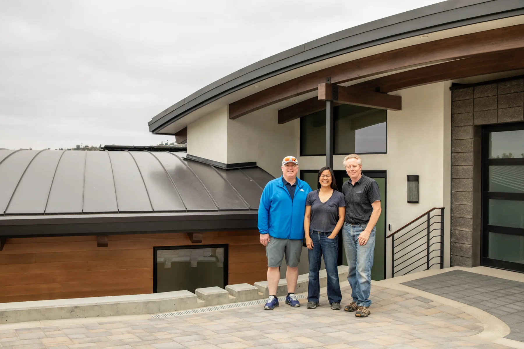 Three people standing in front of a finished custom home