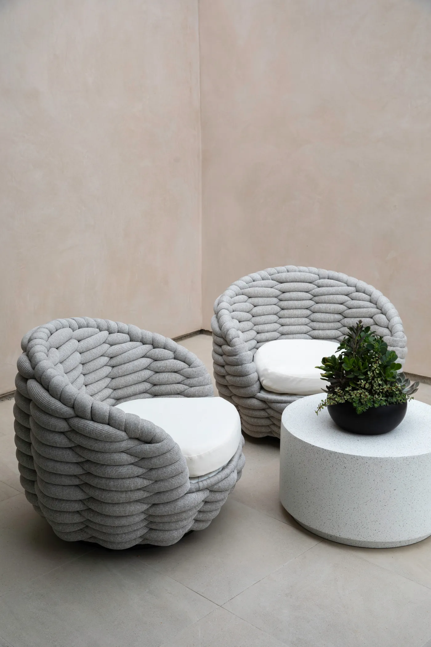 Two woven lounge chairs on a plaster-walled terrace