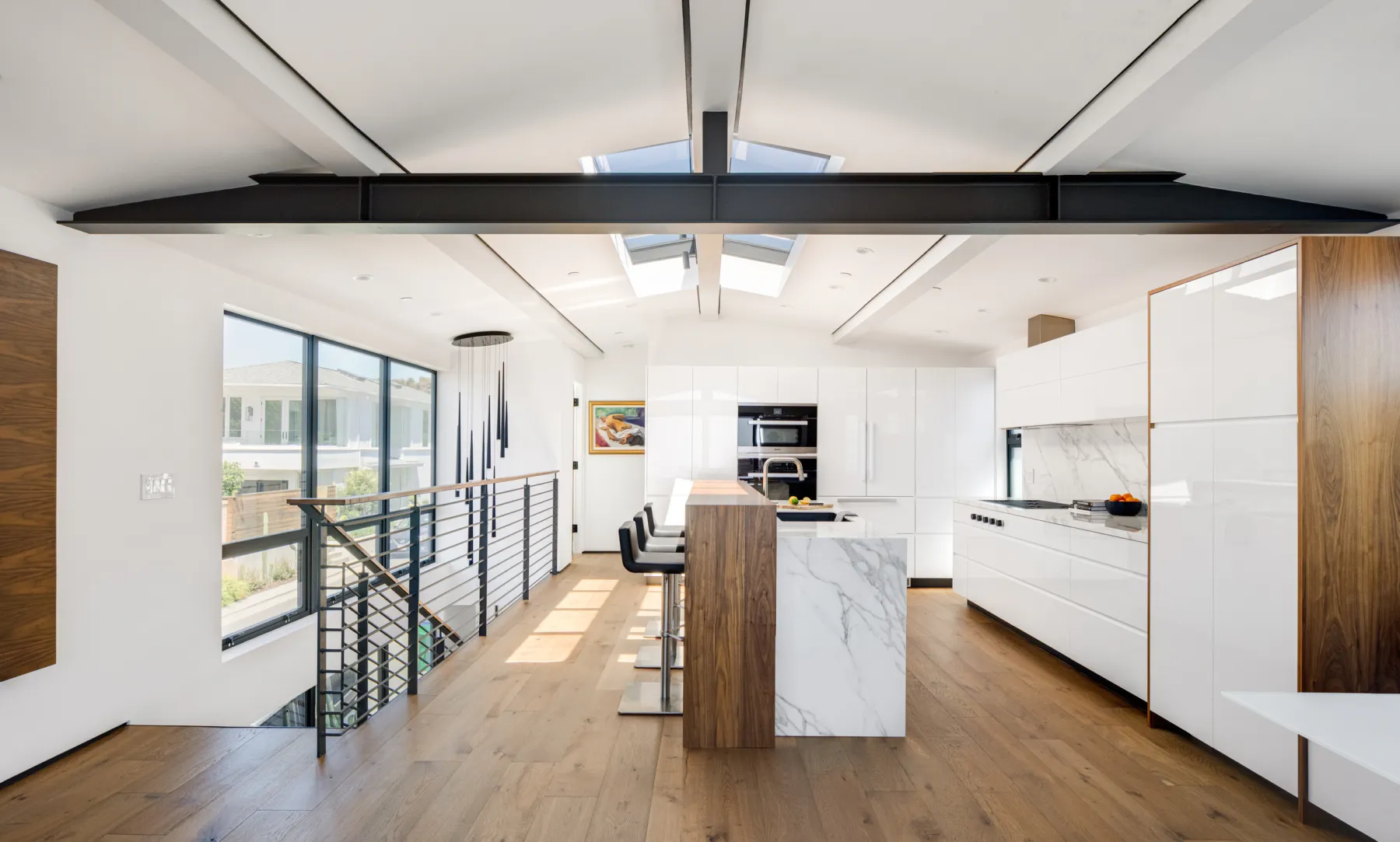 Open kitchen beneath a vaulted ceiling with skylights