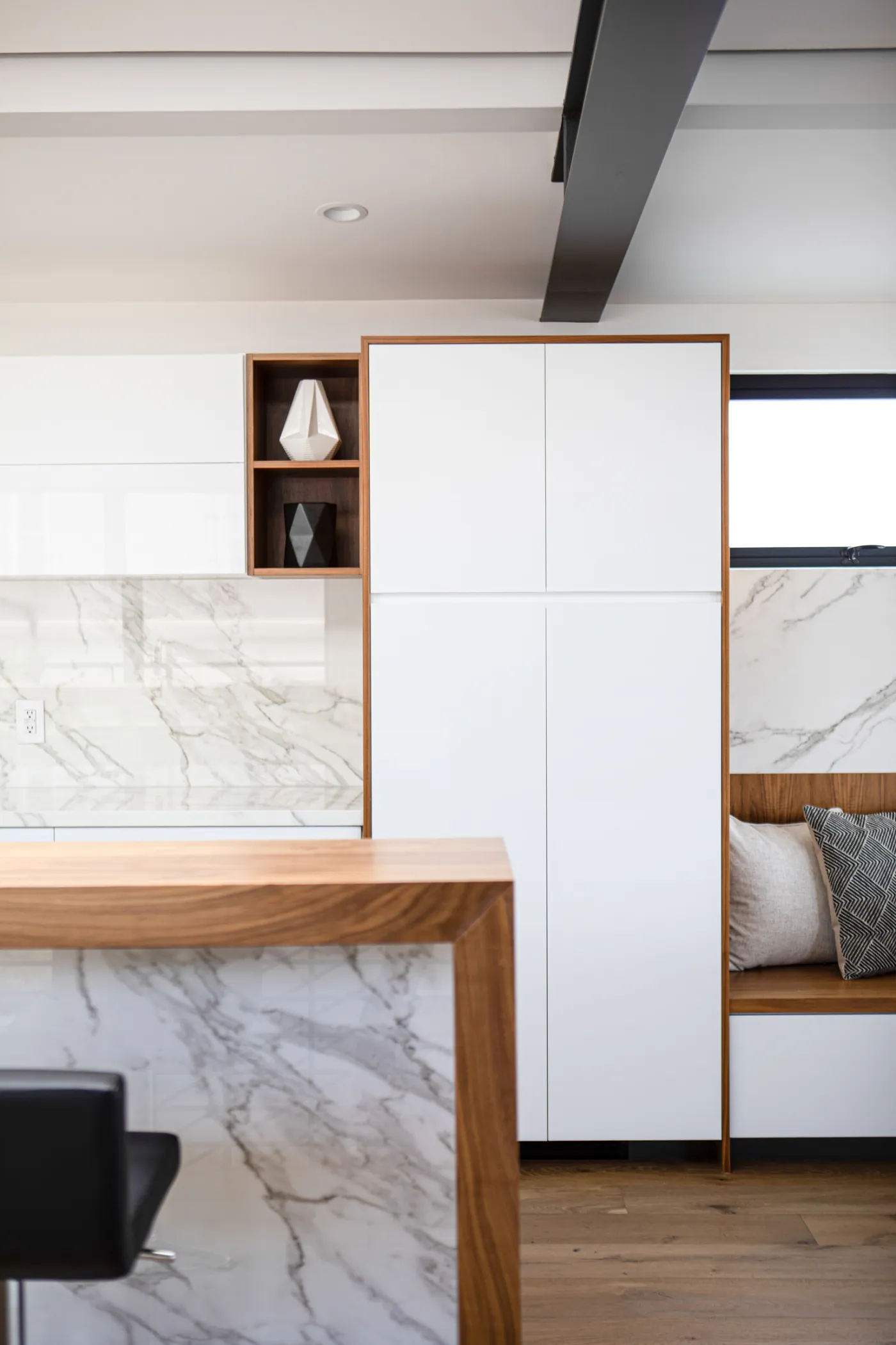 Kitchen with a marble waterfall island and white cabinetry